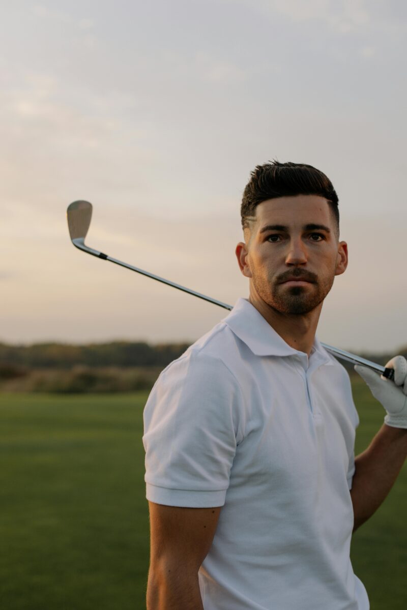Handsome man in white polo shirt holding golf club